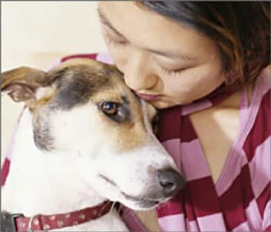 mujer sujetando un perro con collar rojo